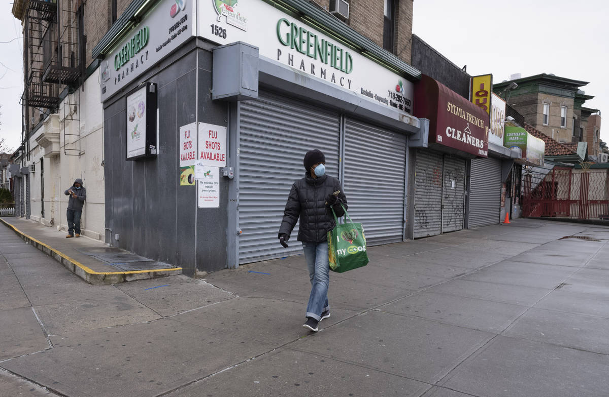 In this Friday, April 3, 2020, photo, a woman walks by local stores during the coronavirus pand ...