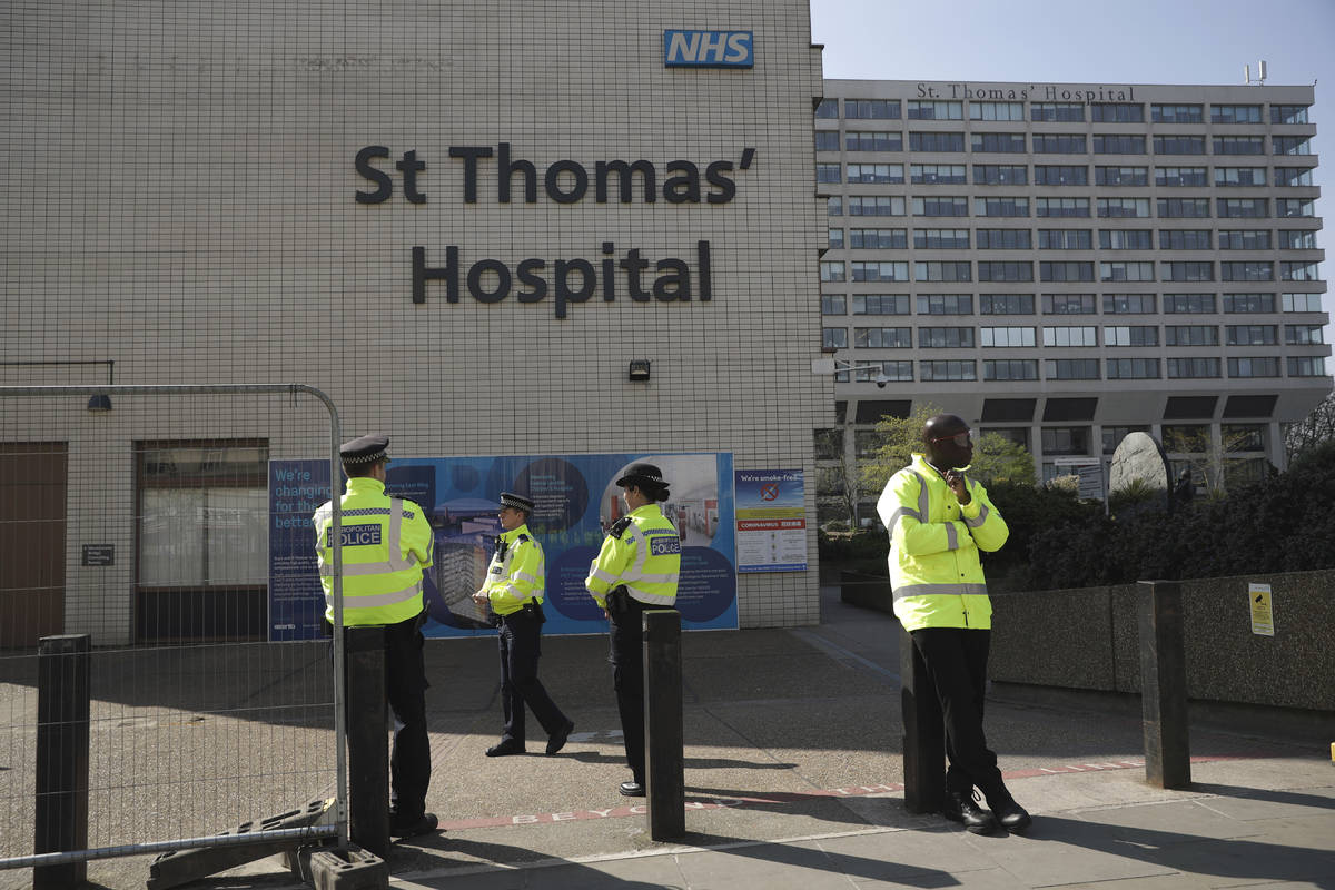 Three police officers at left and a security guard at right guard an entrance outside St Thomas ...