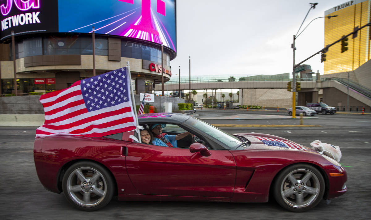 A participant flies an American flag as vehicles make their way up the Las Vegas Strip during t ...