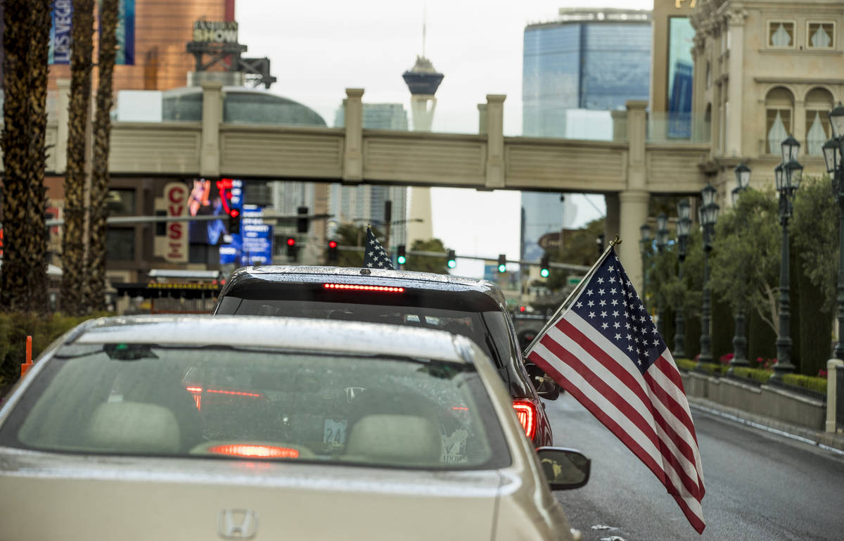 Some participants fly American flags as vehicles make their way up the Las Vegas Strip during t ...