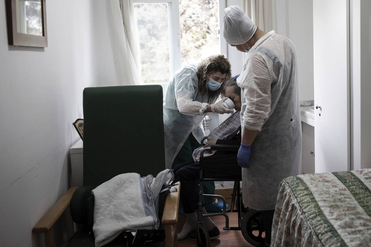 In this April 9, 2020 photo, elderly residency workers Celia, left, and Patricia, right, feed C ...