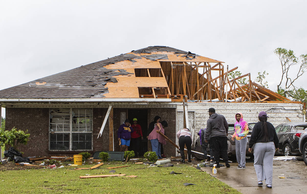 Neighbors and family help to clean a damaged home in Monroe, La. after a tornado ripped through ...