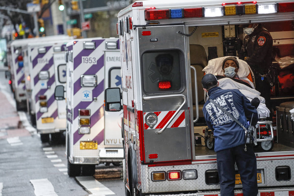 A patient arrives in an ambulance cared for by medical workers wearing personal protective equi ...