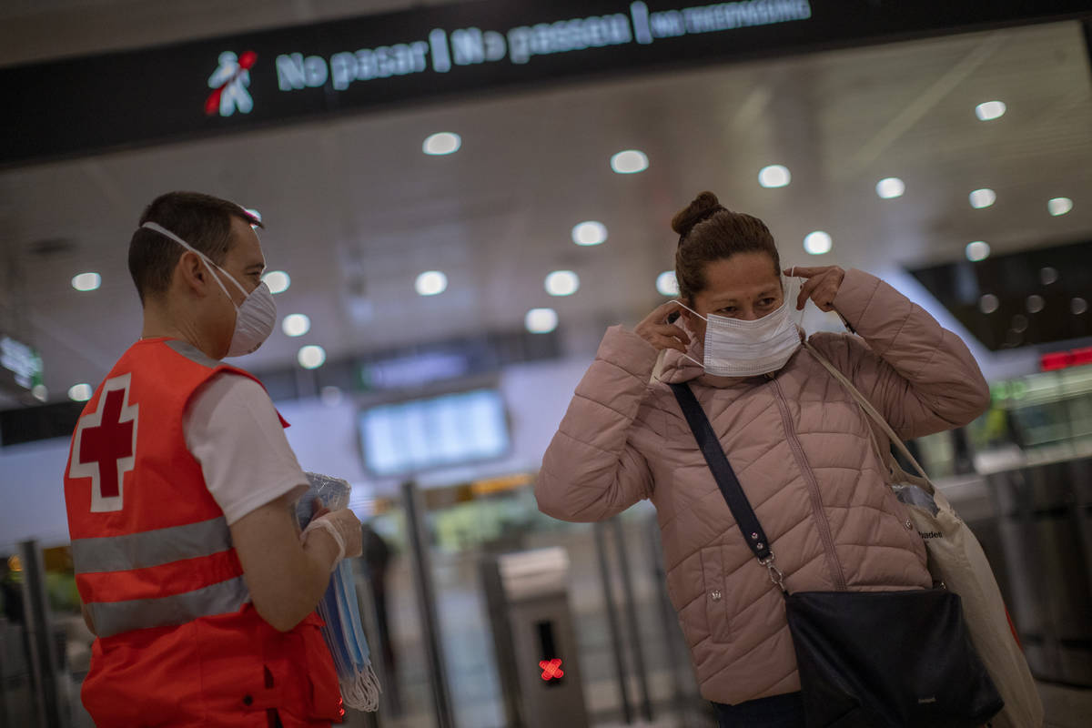 A passenger receives a face mask distributed by a red cross volunteer at the main train station ...