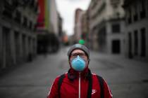 A man wearing a face mask holds a minute of silence for the victims of COVID-19 as the lockdown ...