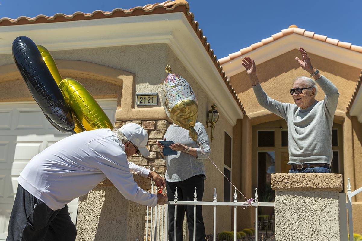 Henry Kronberg, right, waves to friends stopping by his home to help him celebrate his 100th bi ...