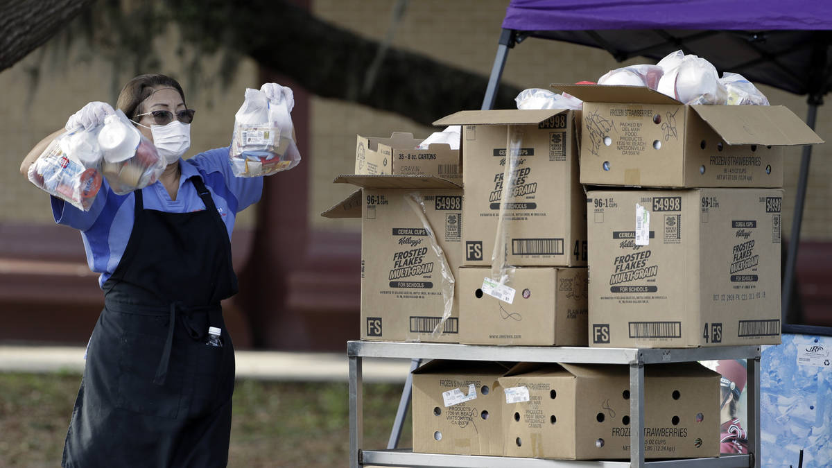 A Hillsborough County lunch room worker holds up food while parents wait in a line Wednesday, A ...