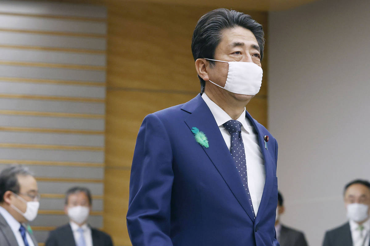 Japanese Prime Minister Shinzo Abe wearing a face mask walks to attend a video conference with ...