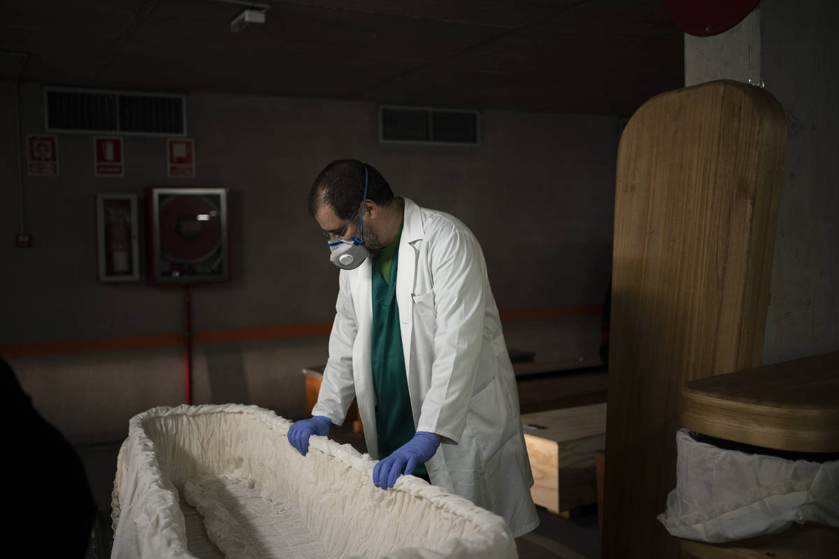 In this April 14, 2020, photo, head mortician Jordi Fernandez prepares a coffin before placing ...