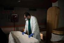 In this April 14, 2020, photo, head mortician Jordi Fernandez prepares a coffin before placing ...