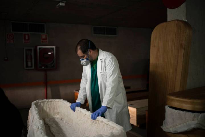 In this April 14, 2020, photo, head mortician Jordi Fernandez prepares a coffin before placing ...