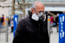 A shopper wears a face mask as he queues at a supermarket due to the coronavirus related lockdo ...