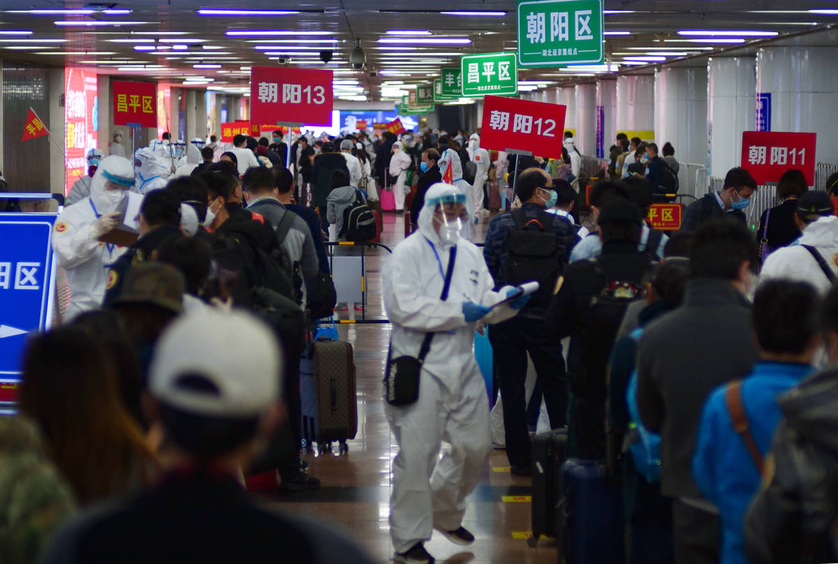 Passengers from Wuhan stand in lines designating where they will quarantine in Beijing, China, ...