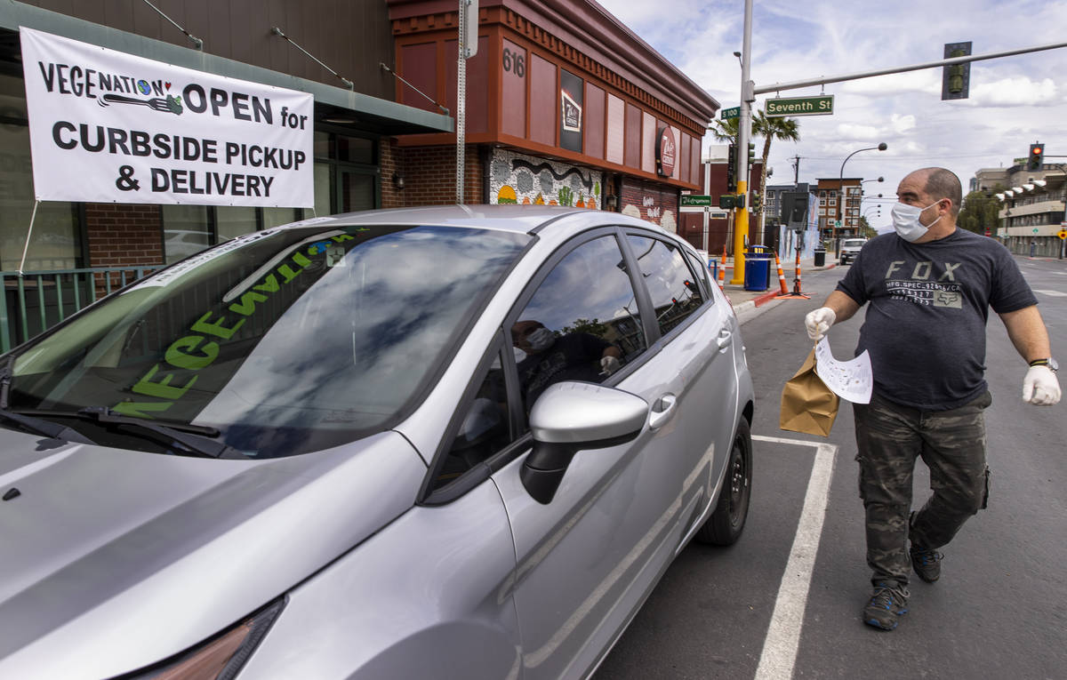 Vegenation customer Mauricio Lu walk around his car after receiving his order as part of their ...