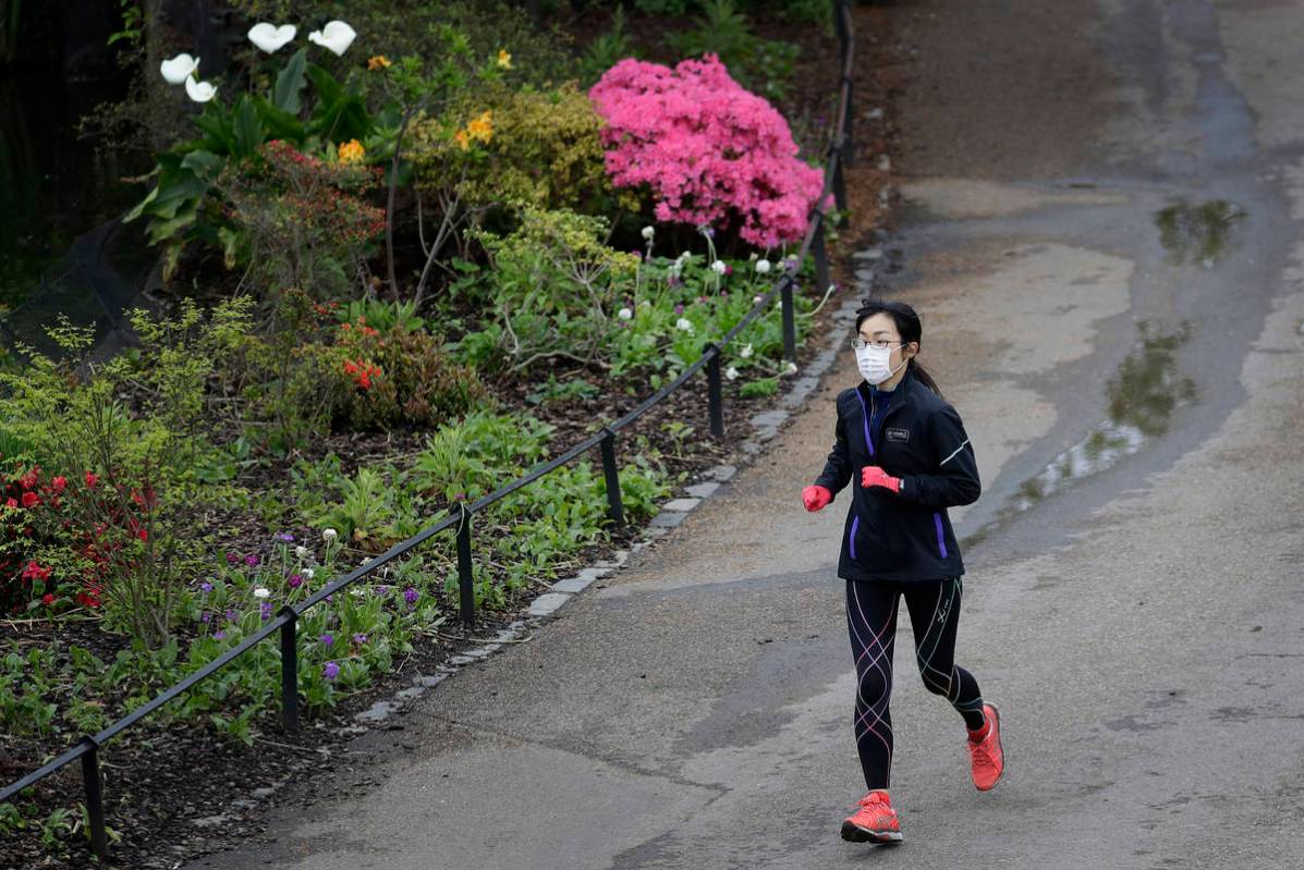 A jogger wears a protective face mask to protect against coronavirus, runs through St James's P ...