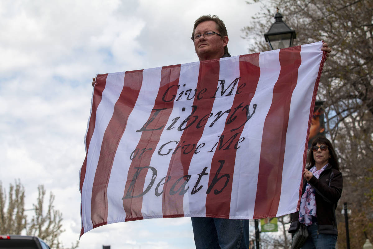 Brandon Camp, 50, holds a flag with the Patrick Henry quote "Give me liberty, or give me d ...