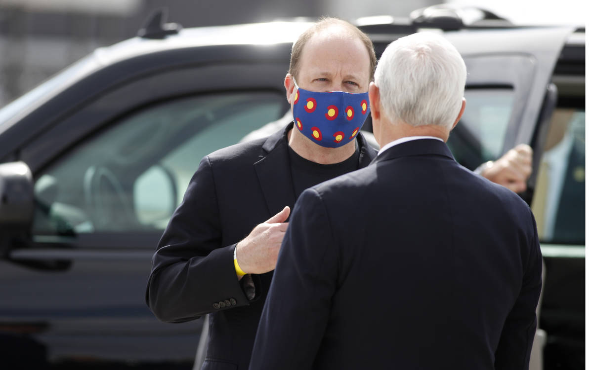 Gov. Jared Polis, left, wears a mask as he talks with Vice President Mike Pence as he arrives a ...