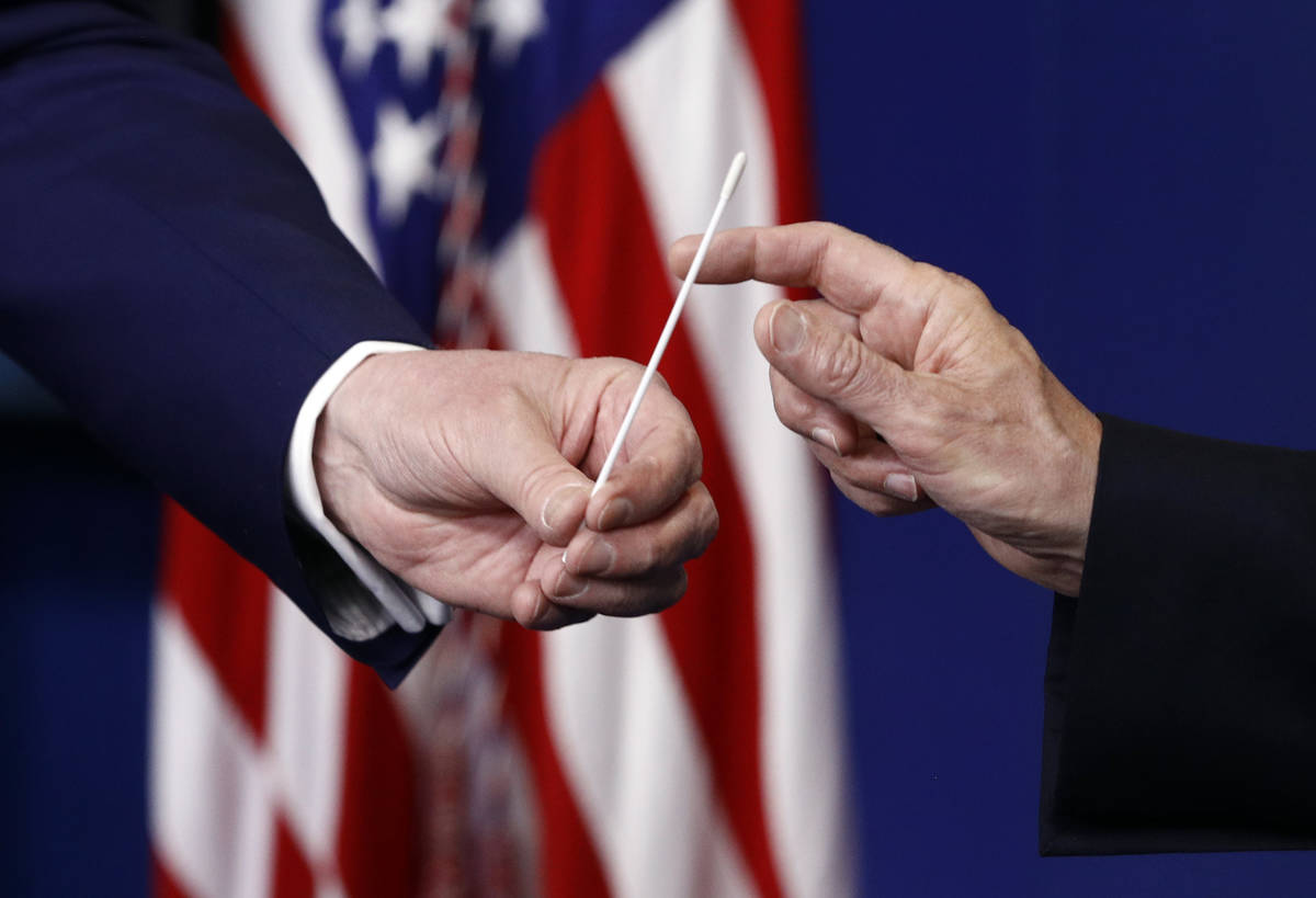 President Donald Trump, left, hands a swab that could be used in coronavirus testing to Vice Pr ...
