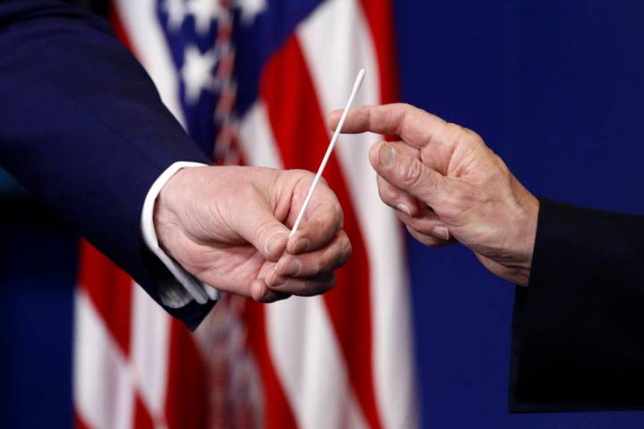 President Donald Trump, left, hands a swab that could be used in coronavirus testing to Vice Pr ...