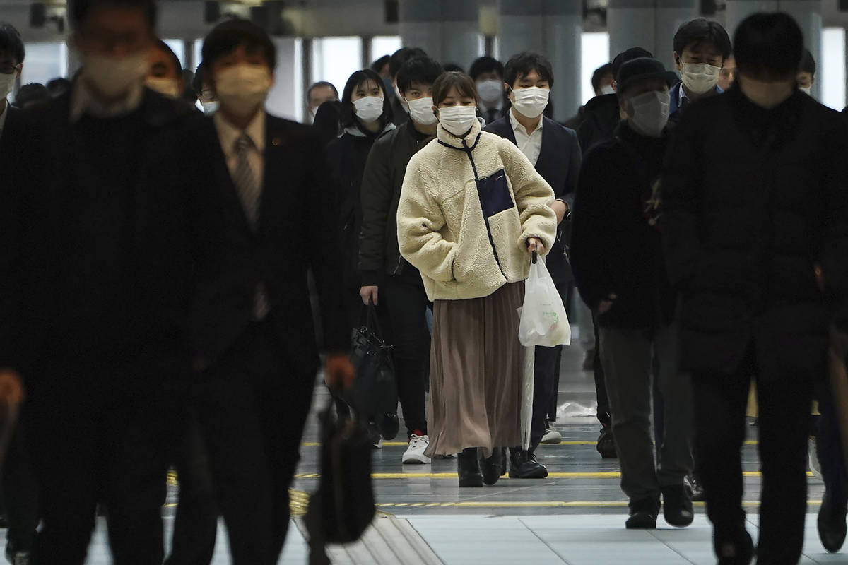 A station passageway is crowded with face mask wearing commuters during a rush hour Monday, Apr ...