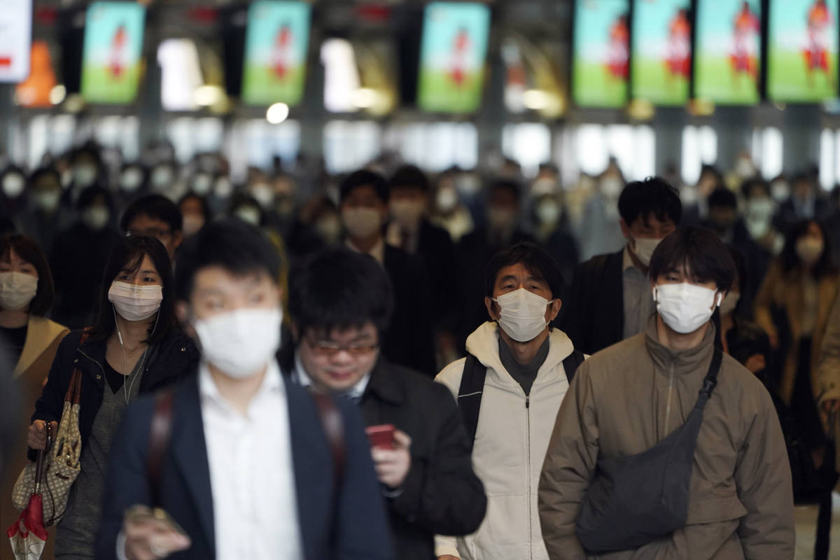 A station passageway is crowded with face mask wearing commuters during a rush hour Monday, Apr ...