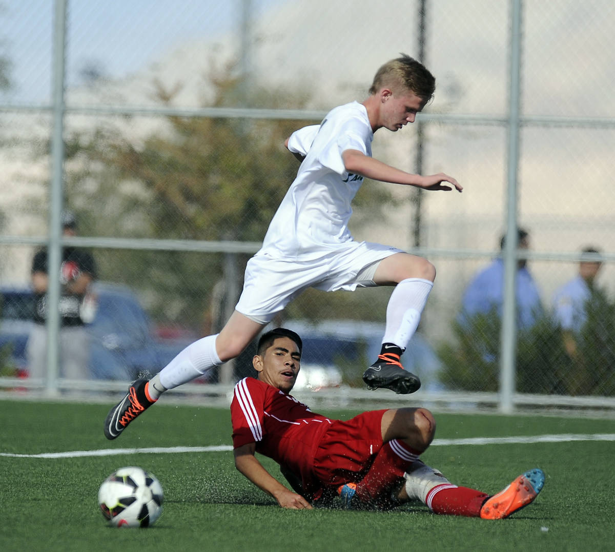 Palo Verde striker Presten Manthey jumps over the slide tackle of Valley defender Steve Favela ...