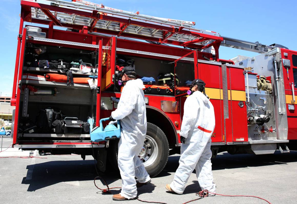 Adam Gunn, left, and Yolie Hernandez, both of Immaculate Restoration, disinfect a Las Vegas Fir ...