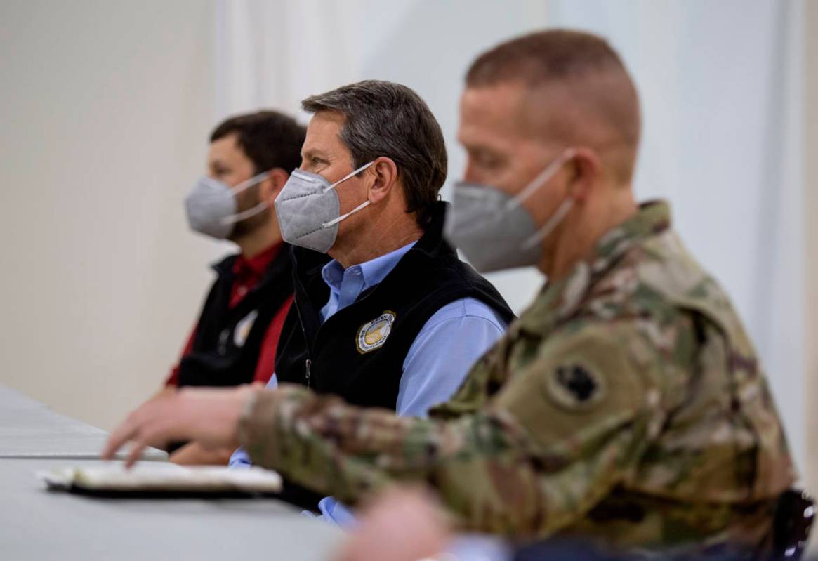 Georgia Gov. Brian Kemp listens to a speaker during a tour of a massive temporary hospital at t ...