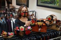In this Wednesday, April 15, 2020, photo, a woman picks an embroidery mask at a fashion studio ...