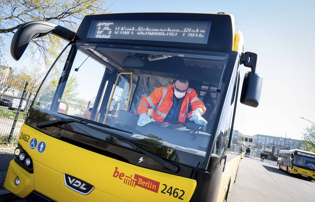 An employee wearing mouth and nose protection and protective gloves cleans the passenger area o ...