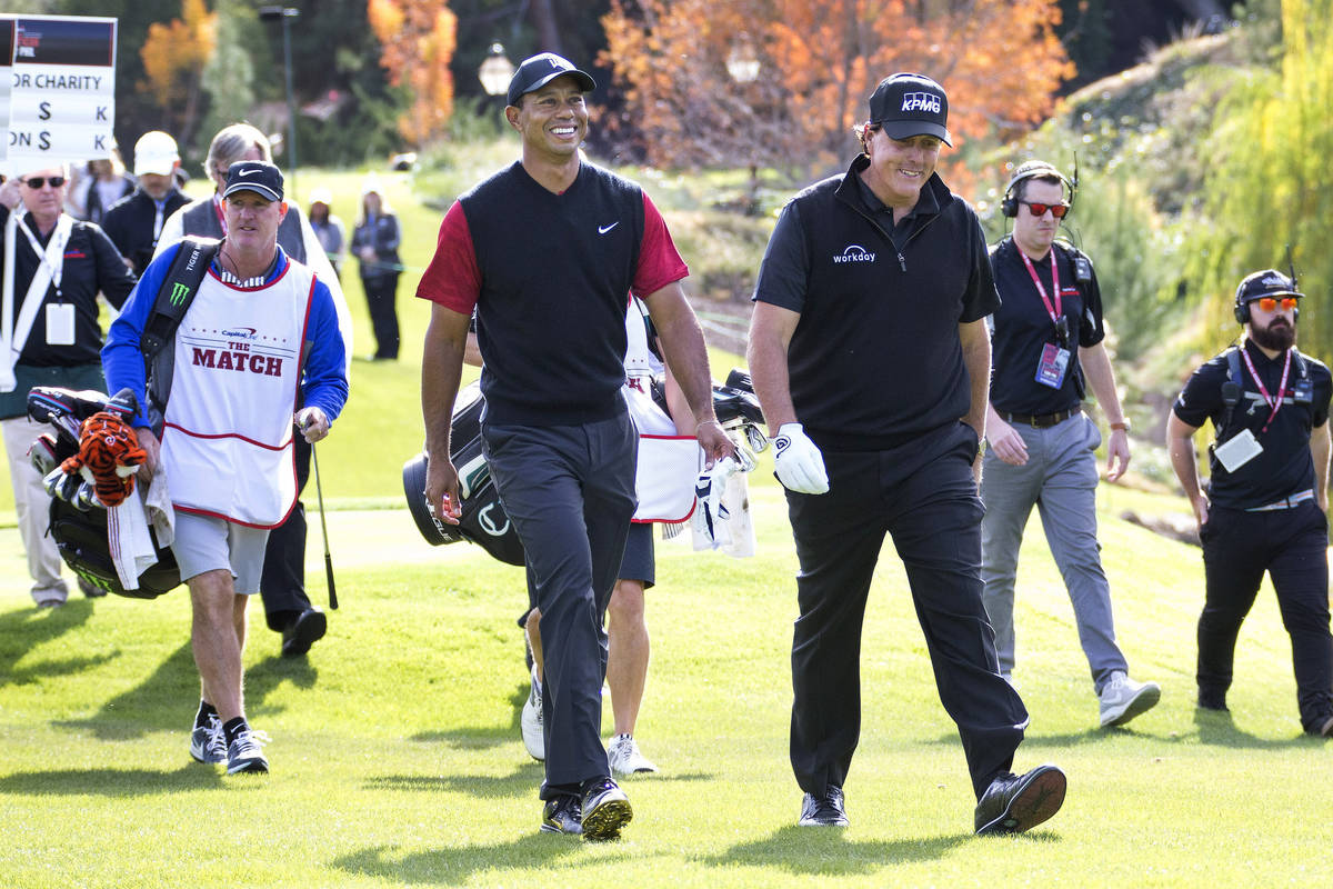 Tiger Woods, left, and Phil Mickelson walk to the fairway after teeing off from the first durin ...