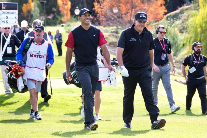 Tiger Woods, left, and Phil Mickelson walk to the fairway after teeing off from the first durin ...