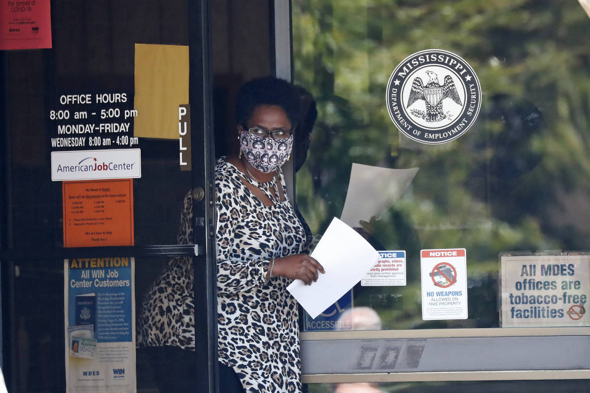 A masked worker at this state WIN job center in Pearl, Miss., holds an unemployment benefit app ...