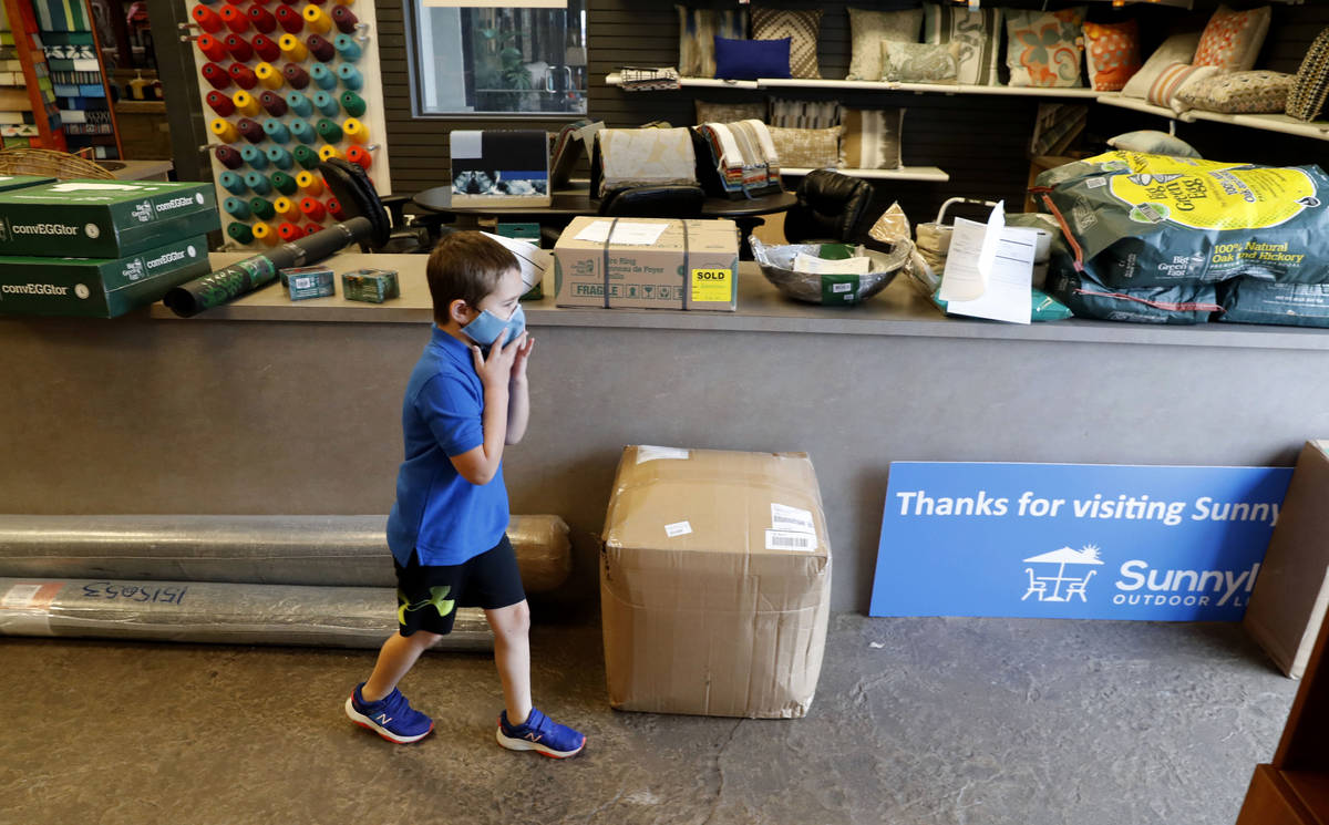 Amid concerns of the spread of COVID-19, kindergartner Eli Schweig, 6, adjusts his mask as help ...