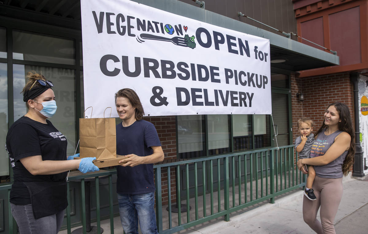 Vegenation's Rebecca Lemperle, left, hands over a food order to customer Matthew Badger with hi ...
