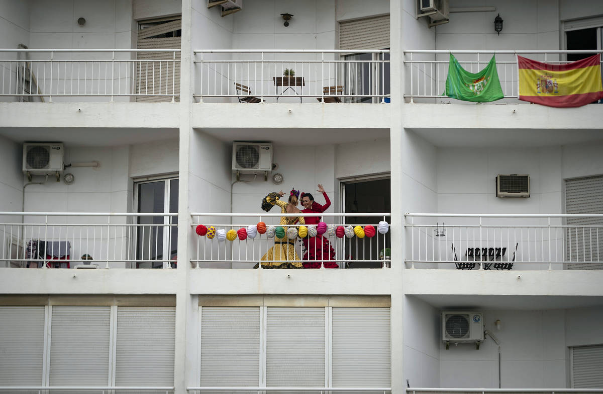 In this photo taken on Saturday April 25, 2020, two women dance on their decorated balcony duri ...