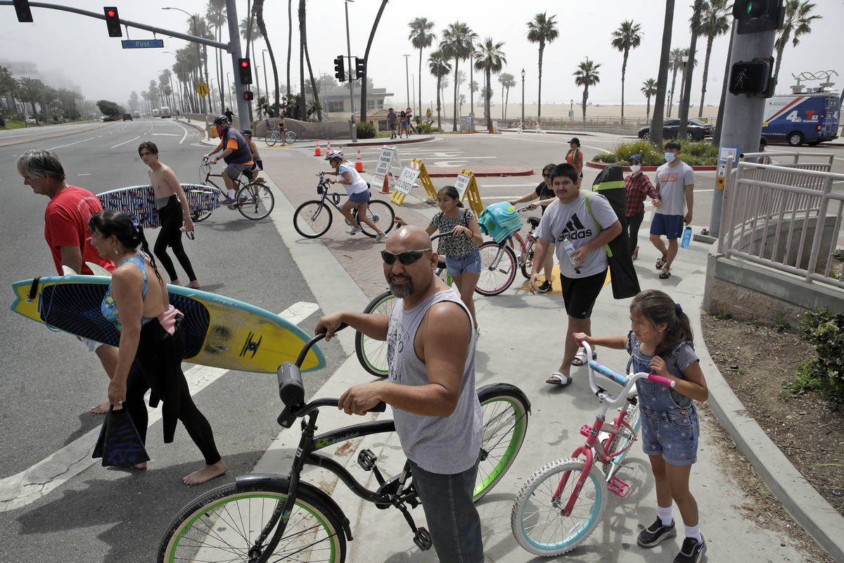 People wait to cross Pacific Coast Highway Sunday, April 26, 2020, in Huntington Beach, Calif. ...