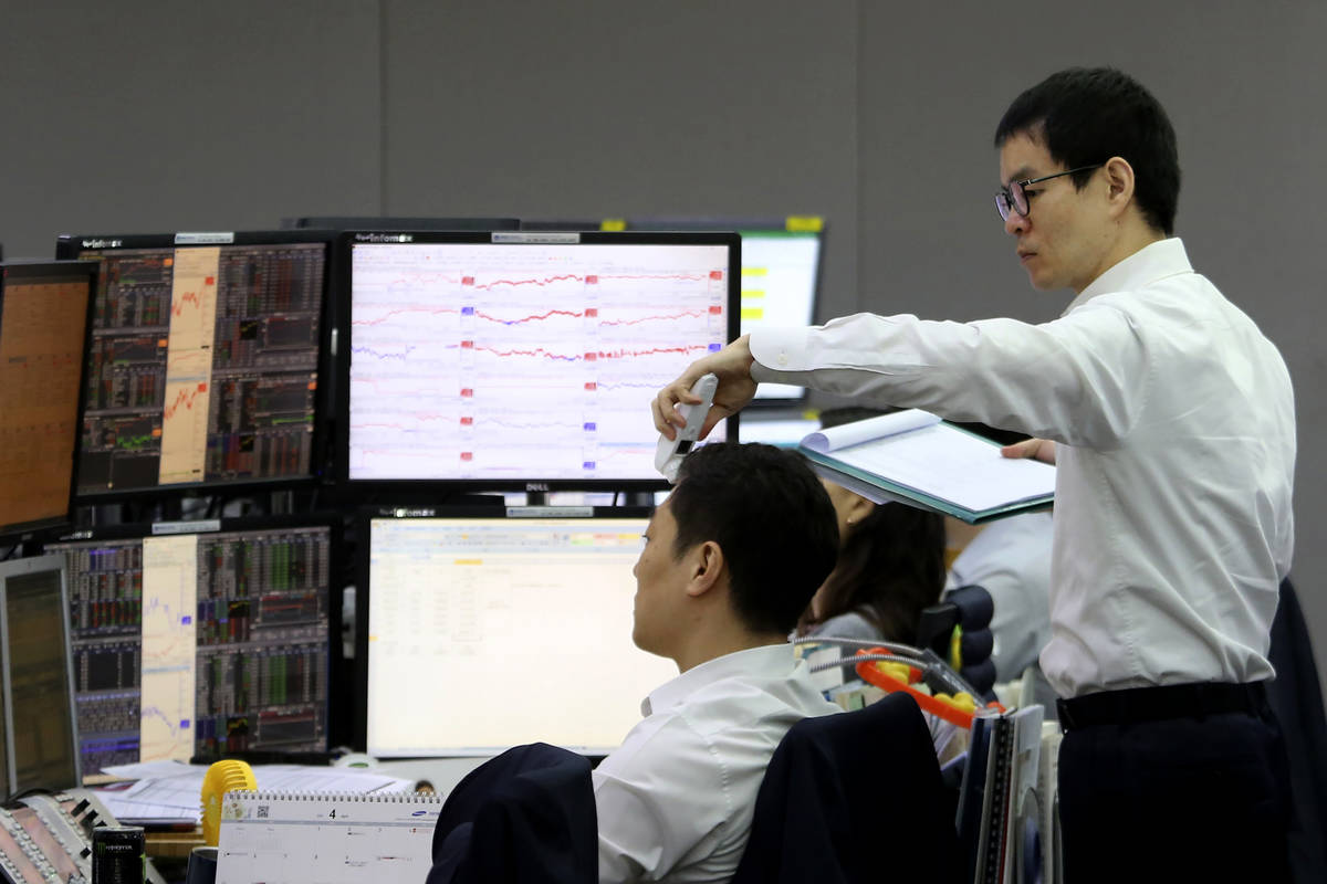 A currency trader checks the temperature of his colleague at the foreign exchange dealing room ...