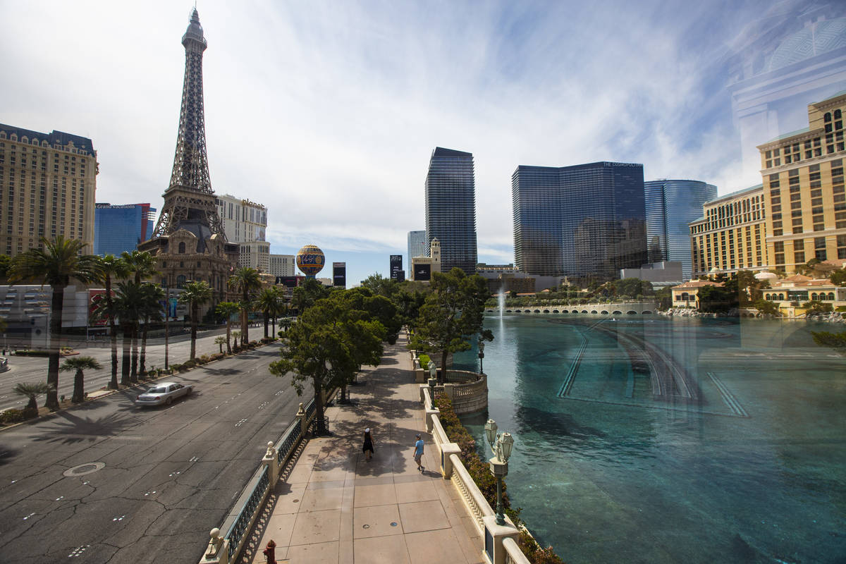 People pass by the Bellagio while walking the Las Vegas Strip on Thursday, April 16, 2020. (Cha ...