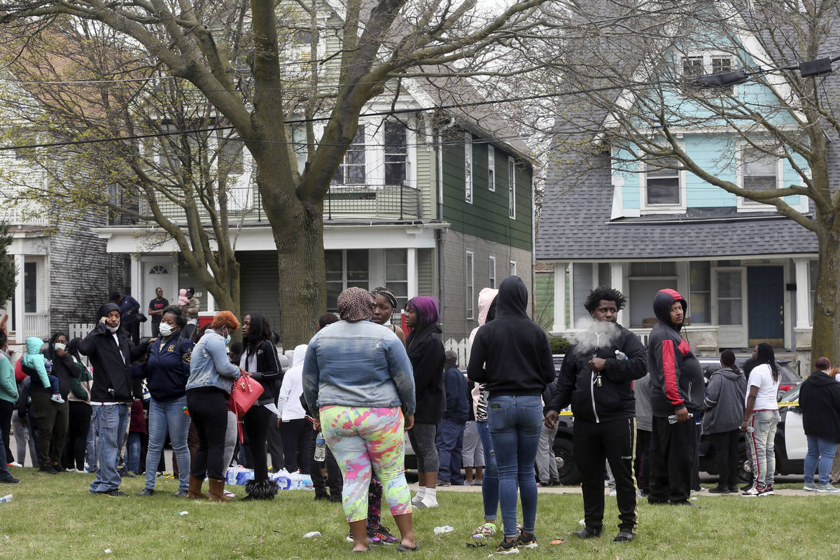 A crowd gathers at the scene of a shooting where five people were killed in Milwaukee, Wis., Mo ...