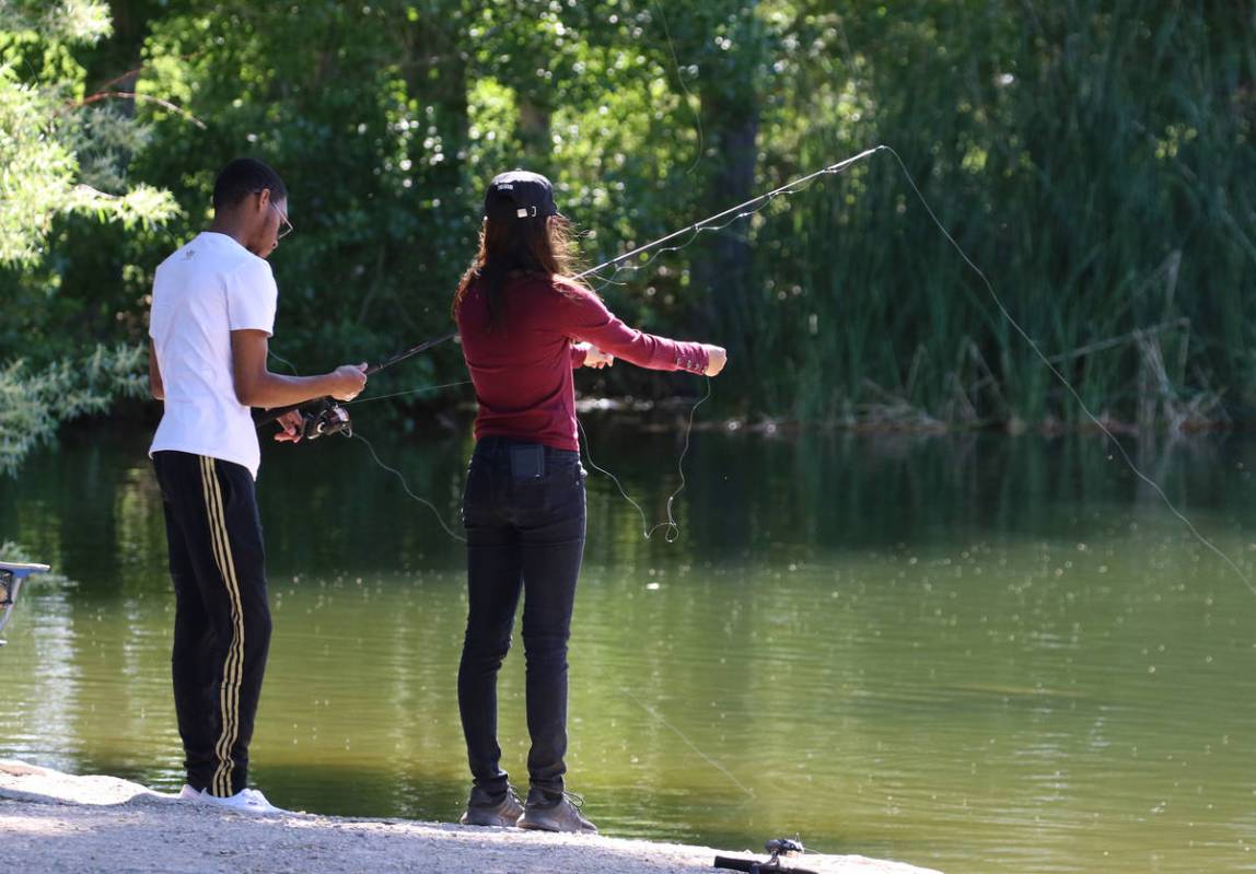 Michael Caldwell, left, fishes as his friend Nan Sukcharoen prepares her fishing rod at Floyd L ...