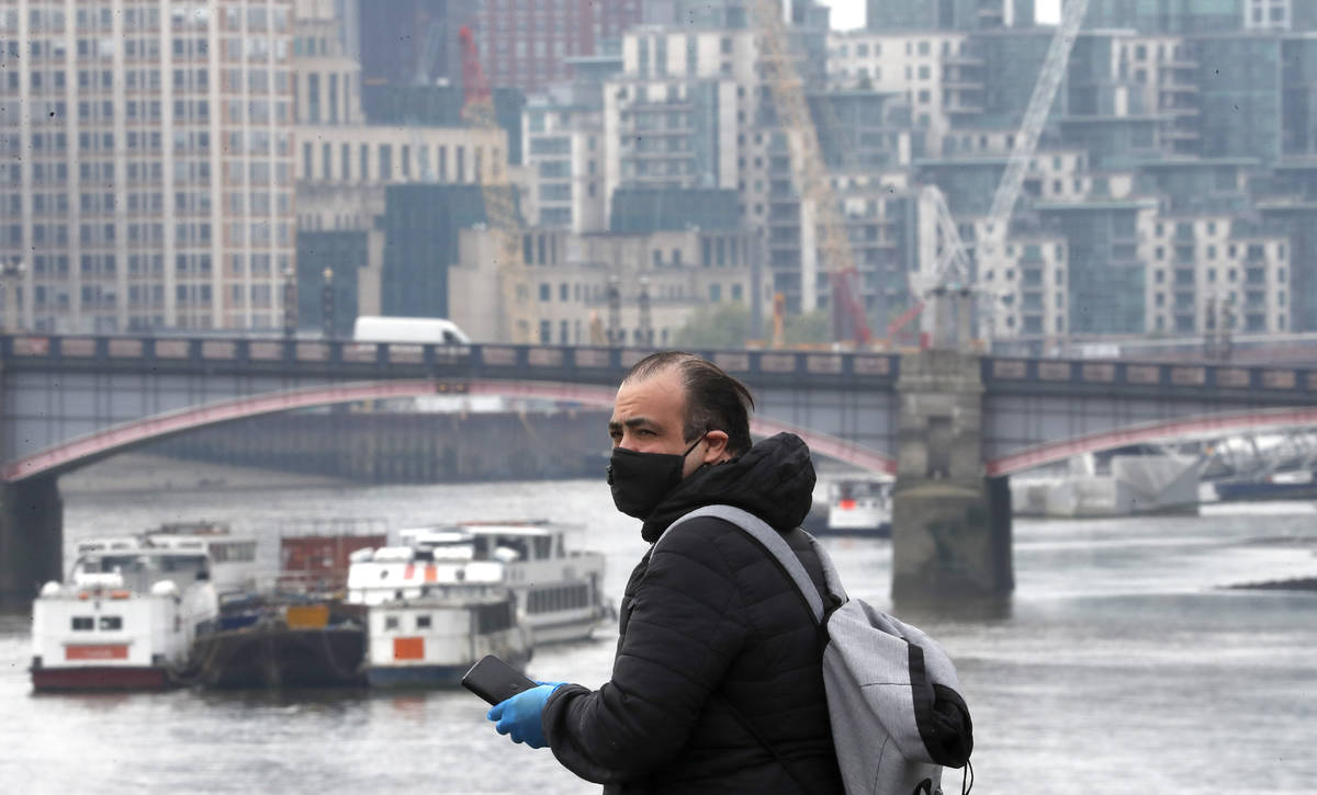 A man with a face walks across Westminster Bridge in London, Monday, April 27, 2020. While Brit ...