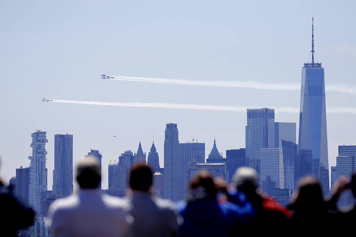 People watch as a formation of the Blue Angels and Thunderbirds flight teams pass in front of t ...