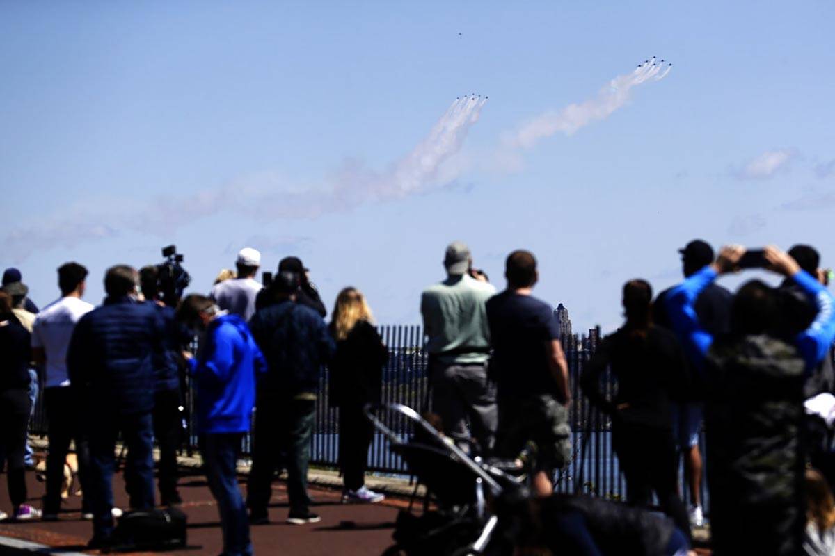 People watch as a formation of the Blue Angels and Thunderbirds flight teams pass in front of t ...