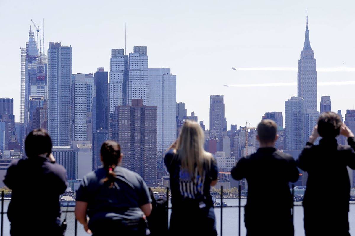 People watch as a formation of the Blue Angels and Thunderbirds flight teams pass in front of t ...