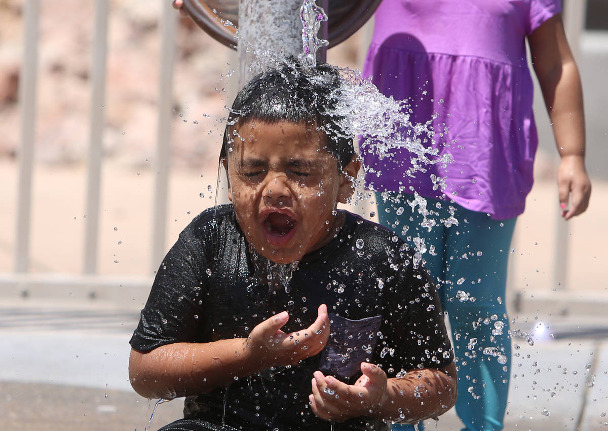 CJ Ceniceros, 6, cools himself while playing with his sister Talia, 3, at Lorenzi Park on Frida ...