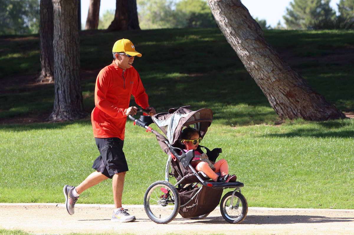 Mel Feliciano pushes his 3-year-old daughter Khaely's stroller as he runs at Sunset Park during ...