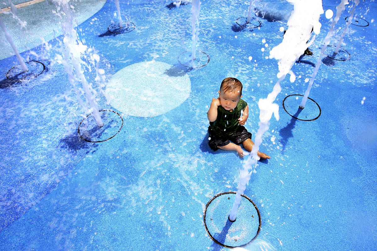 Eleven-month-old Parker Gurdison sits amid cooling columns of water at the Town Square water fo ...