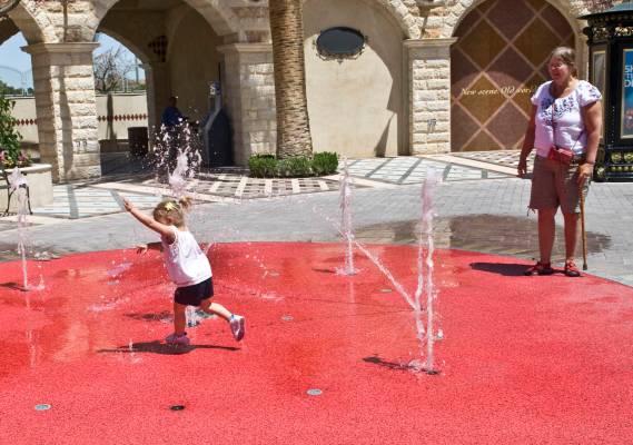 Two-year-old Emma Skufca runs through the water feature at Tivoli Village under the watchful ey ...