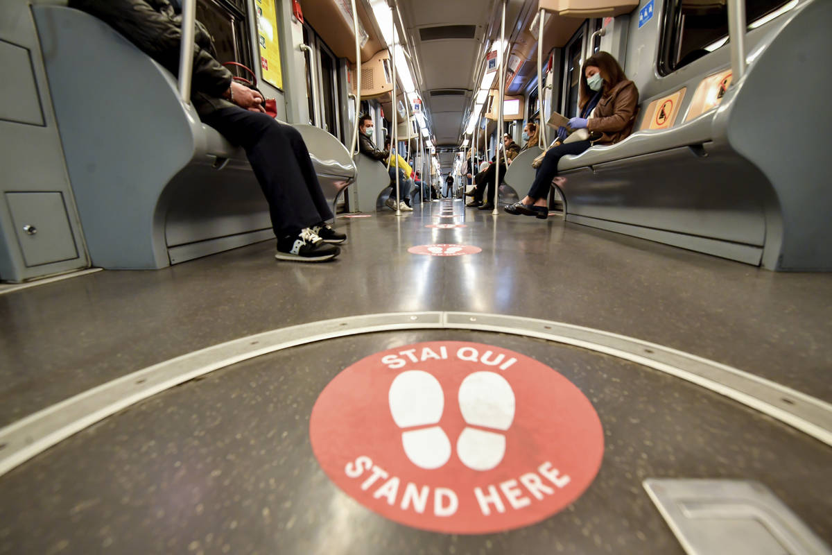 Passengers takes their seats apart from each other as red signs mark the right distances to kee ...